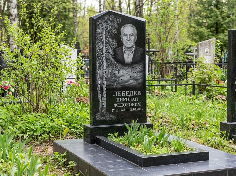 Памятник с гравировкой берёзы: вертикальная стела со скошенным верхом — берёза и стая птиц в небе, гранитный цоколь с тёмной плиткой, работа «Лебедев» в Ульяновске