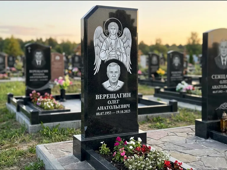 Памятник с гравировкой иконы: стела с резным навершием и нимбом в золоте — гравировка образа Спасителя, высокие разросшиеся туи полукругом, работа «Мельникова» в Ульяновске