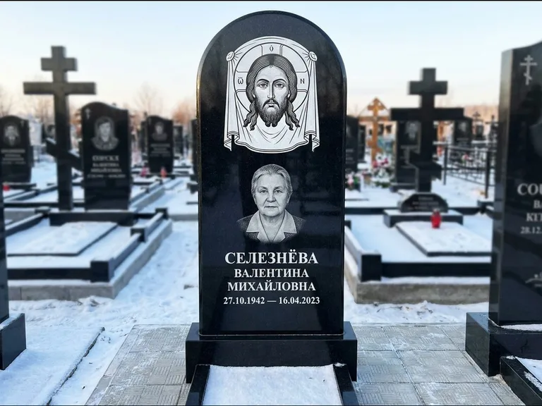 Памятник с гравировкой иконы: небольшая скромная одиночная стела с именной иконой — золочёный нимб на образе, аккуратный участок с газоном, работа «Ковалёв» в Ульяновске