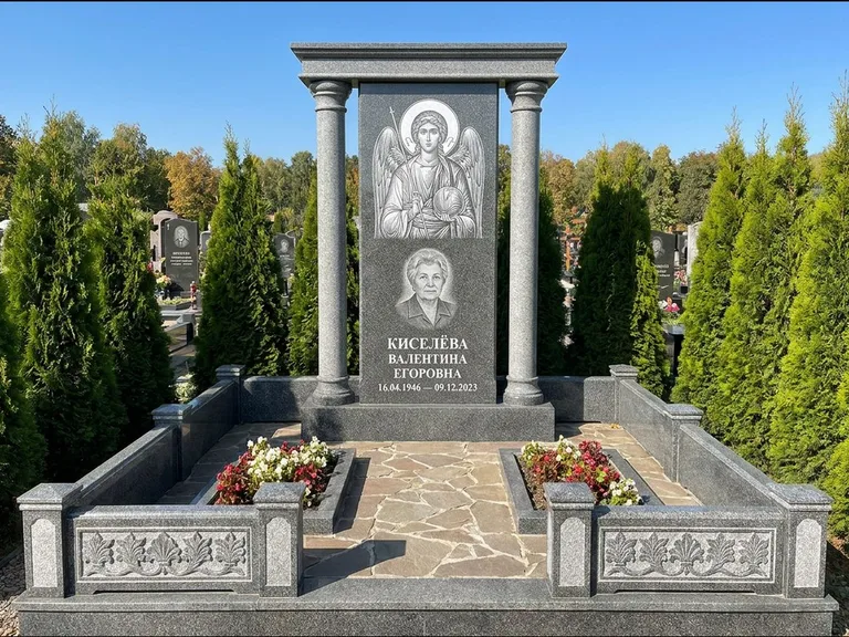 Памятник с гравировкой иконы: массивная стела с двускатным навершием-домиком — гравировка Николая Чудотворца, живая изгородь из туи, работа «Журавлёв» в Ульяновске